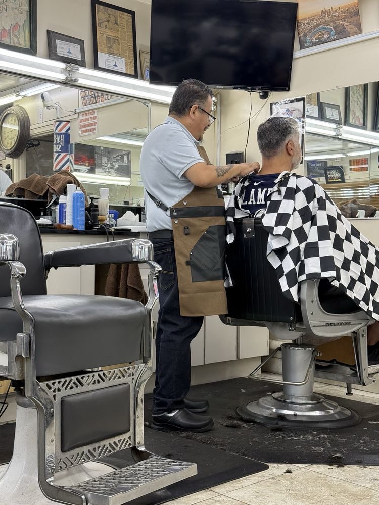 One of our barbers giving a customer a haircut in a vintage chrome barber chair
