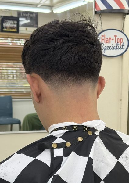A fresh low fade under our Flat-Top Specialist sign